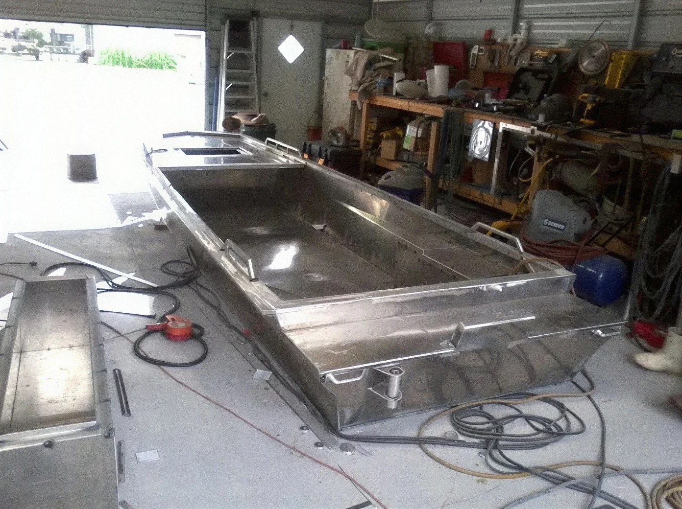 Open aluminum hull with welded seating and flooring inside the workshop